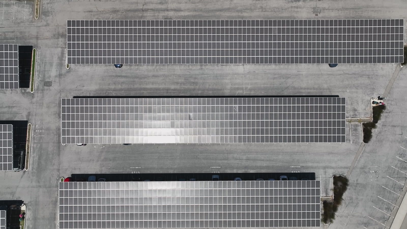 Expansive aerial view of solar farm with rows of panels and pond